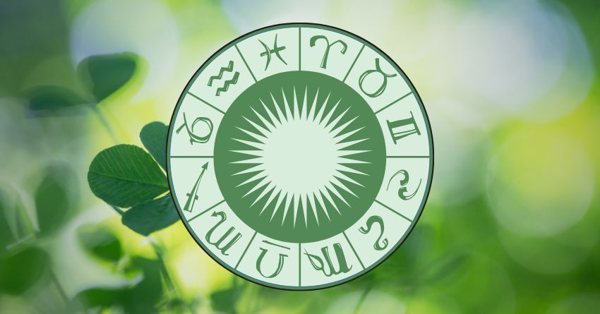 Green zodiac wheel with astrological symbols surrounded by fresh leaves and soft natural light